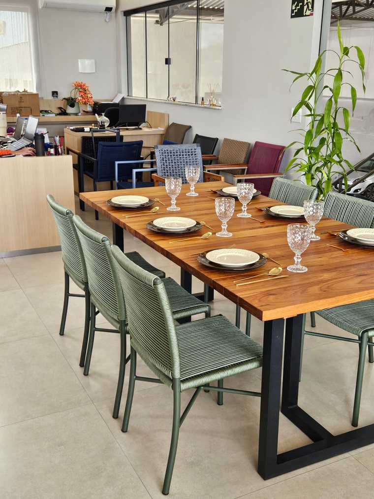 Mesa de jantar de madeira posta, com cadeiras de fibra sintética verde ao redor