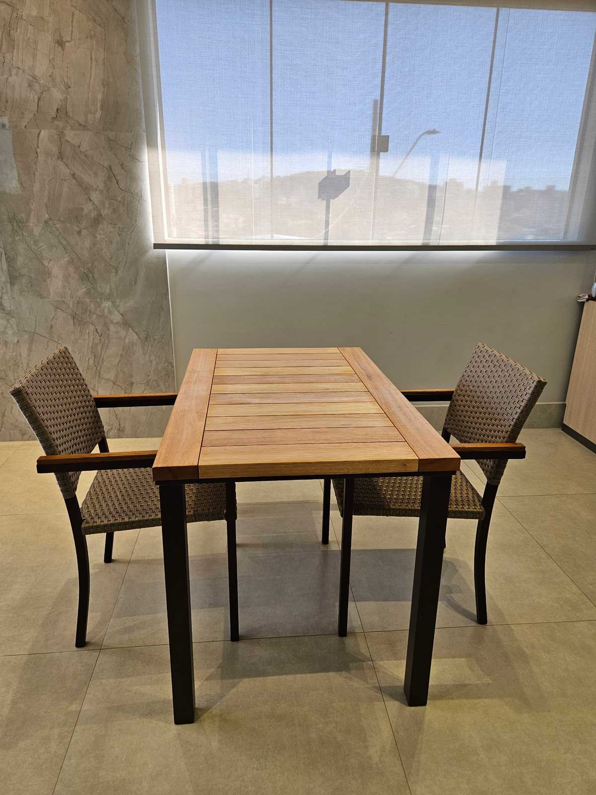 Mesa de madeira com duas cadeiras de fibra sintética em ambiente claro