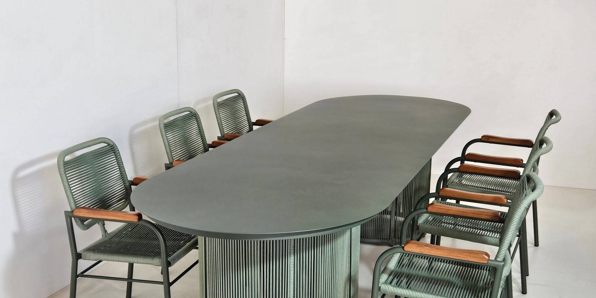 Mesa longa com cadeiras de fibra sintética verde em ambiente amplo e claro