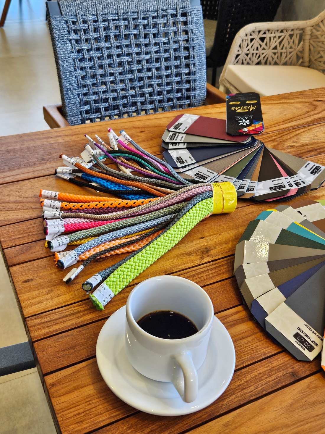 Cartela com dezenas de amostras de cores de trama e acabamentos da WE Móveis sobre mesa de madeira
